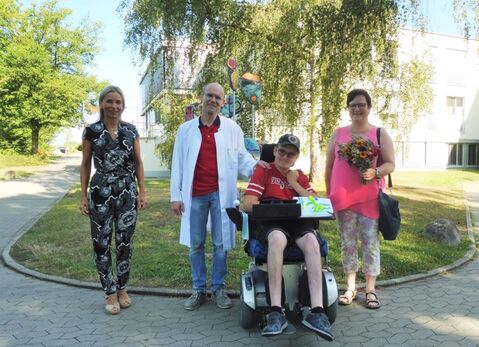 V.l. Barbara Martetschläger, Stellvertretung der Geschäftsführung und Dr. Wolfgang Elmlinger bedankten sich mit einem Präsent bei Simon Oswald und gratulierten ihm zu seinem bereits 25. Reha-Aufenthalt im Hegau-Jugendwerk. Auch seine Mutter Brita, die ihren Sohn bei jeder Reha zur Seite stand bekam als Dankeschön ein Blumensträußchen überreicht. Bild: Kranz